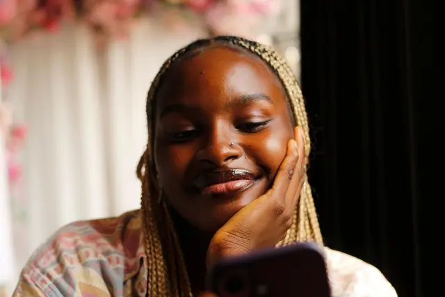 A young woman smiling at her phone in a café in Abuja